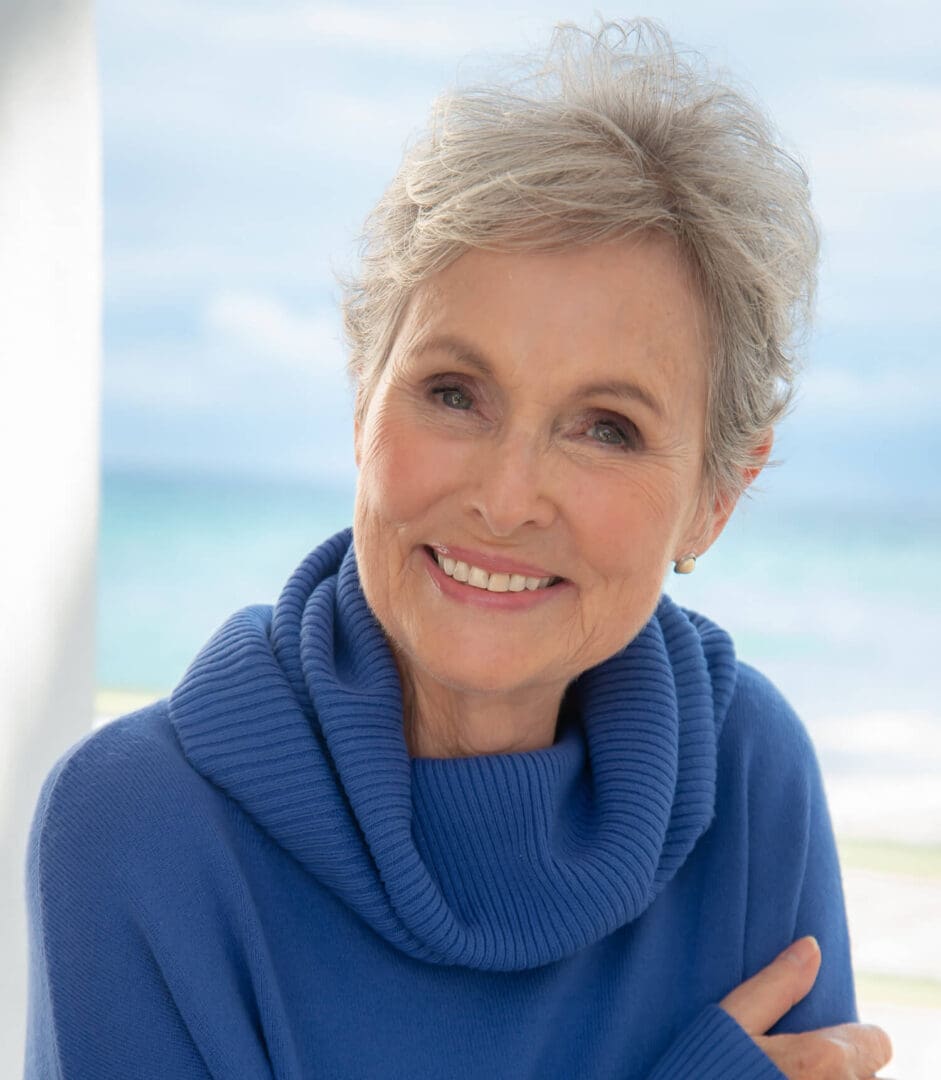 A woman with white hair wearing a blue sweater. A woman with white hair wearing a blue sweater.