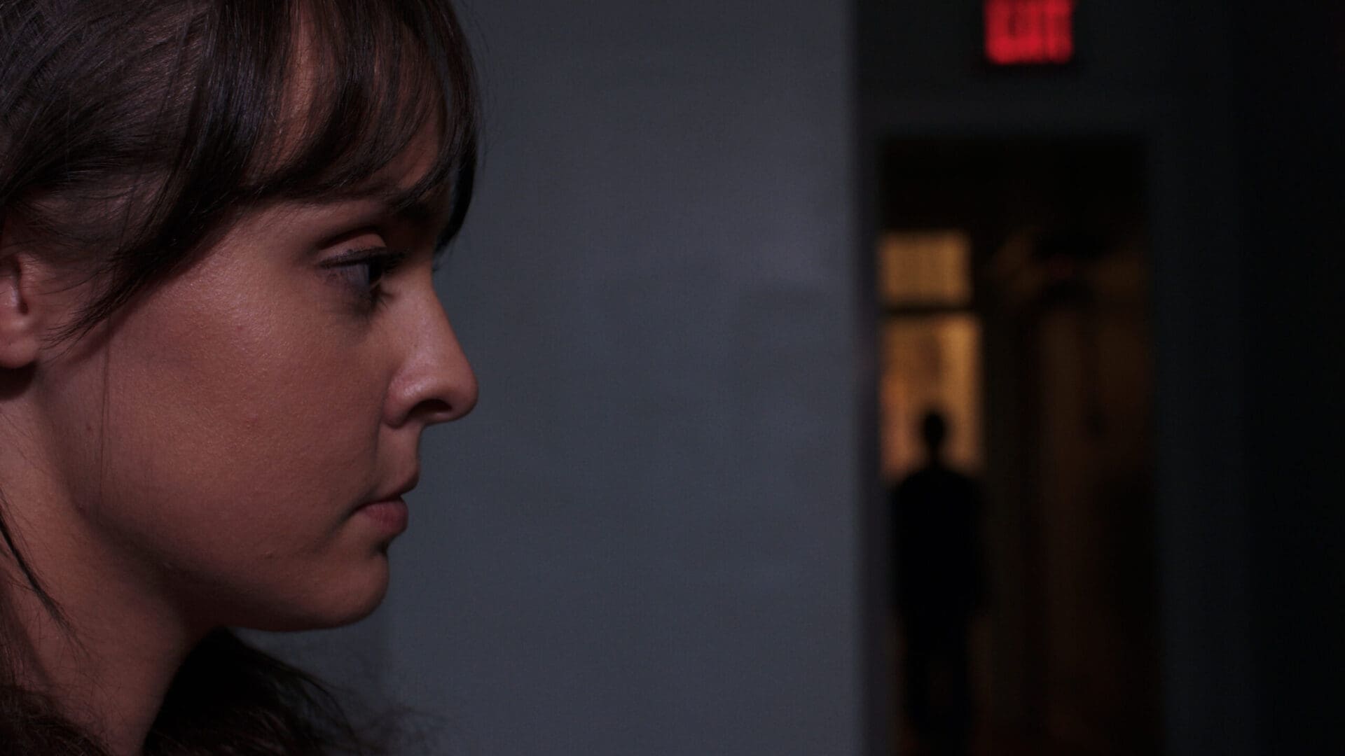 A woman looking to her left in the dark. A woman looking to her left in the dark.